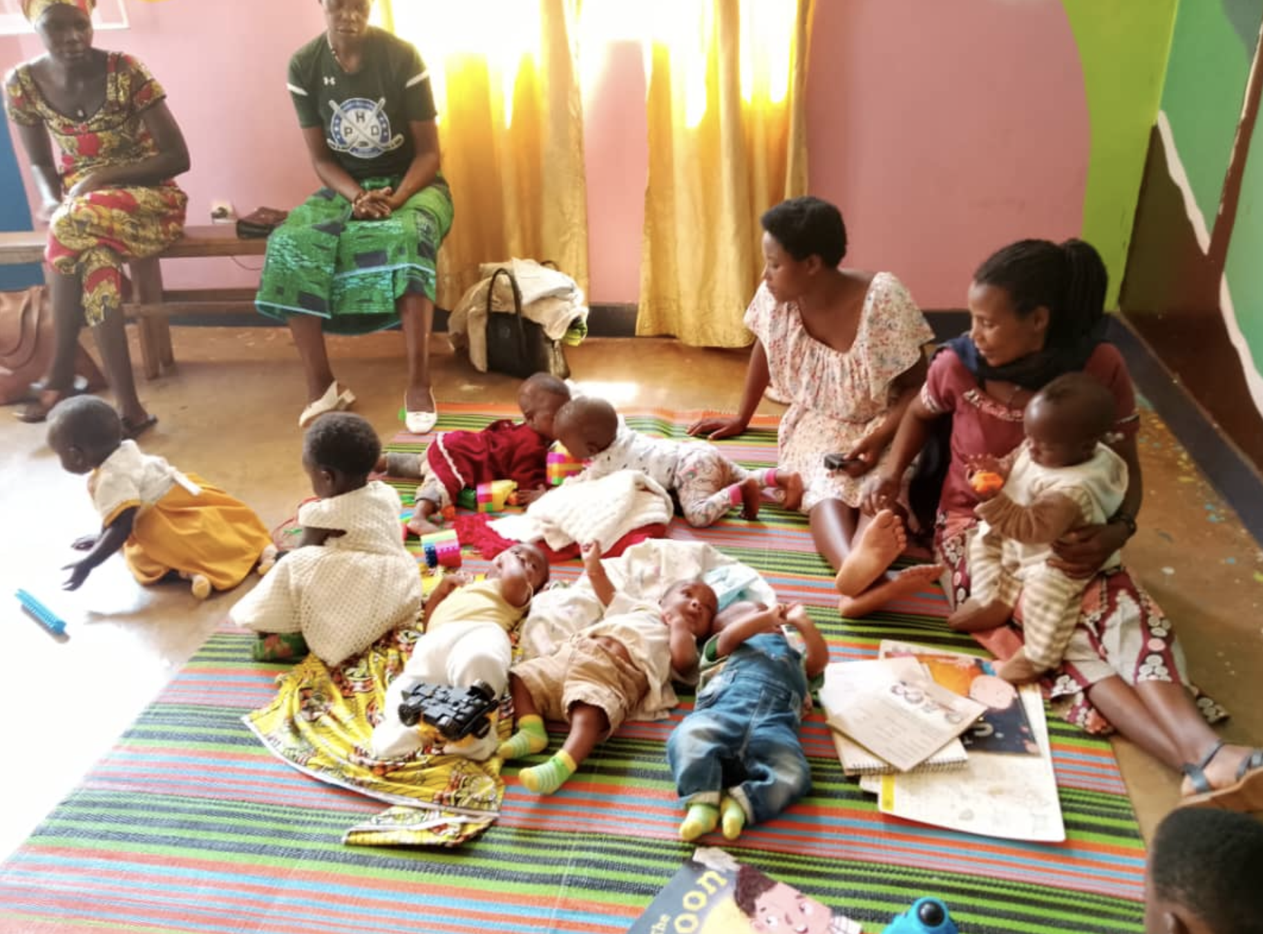 Mothers sitting with babies and toddlers on a mat in the childcare room