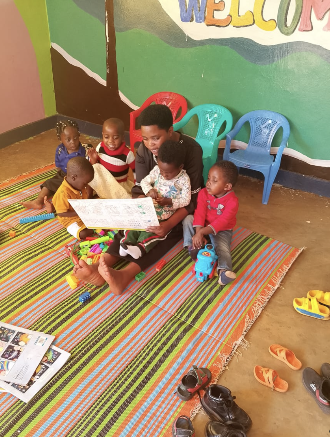 A caregiver reading a picture book to a group of young children