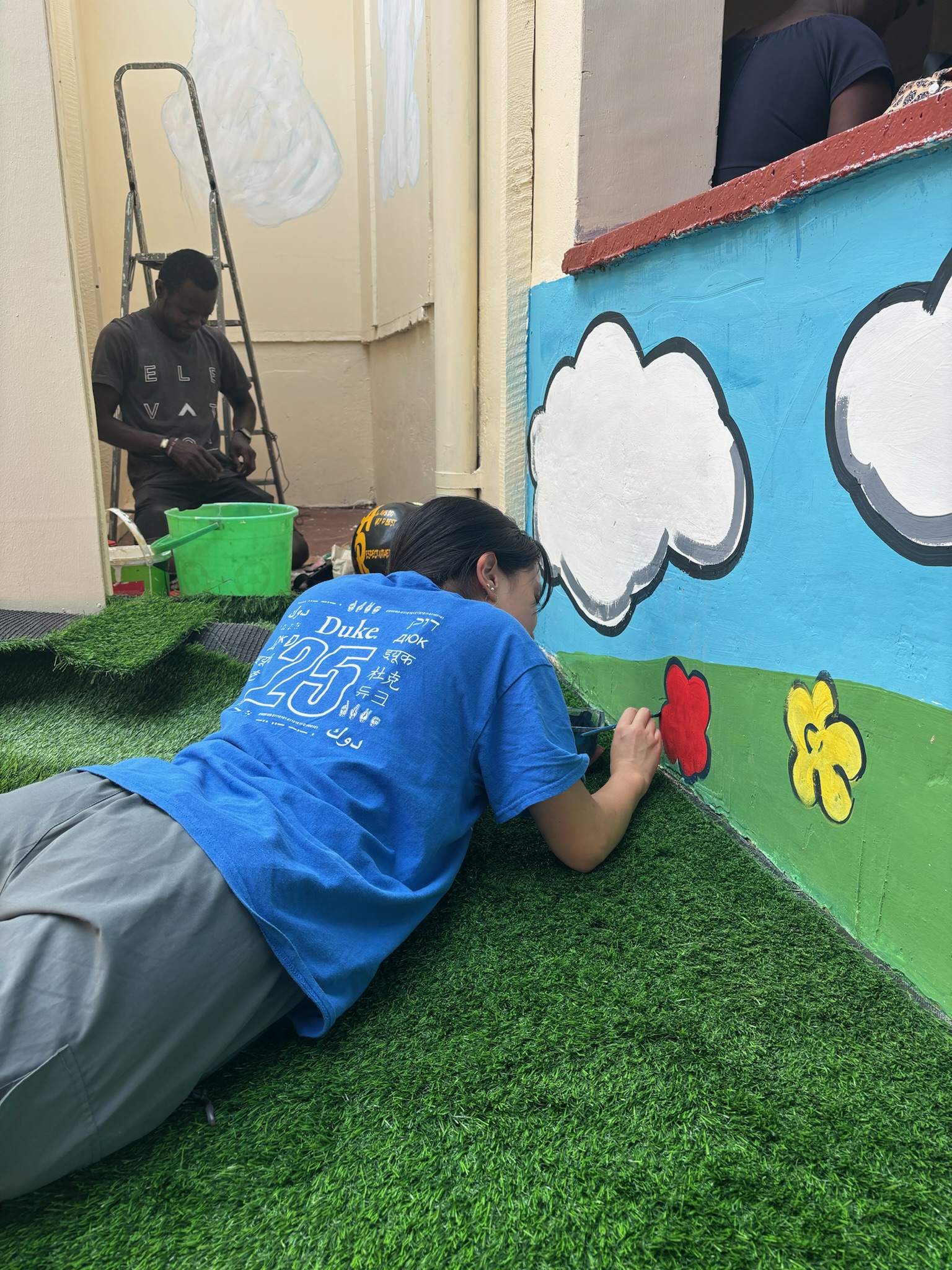 Volunteers painting colorful murals at Lumumba childcare center