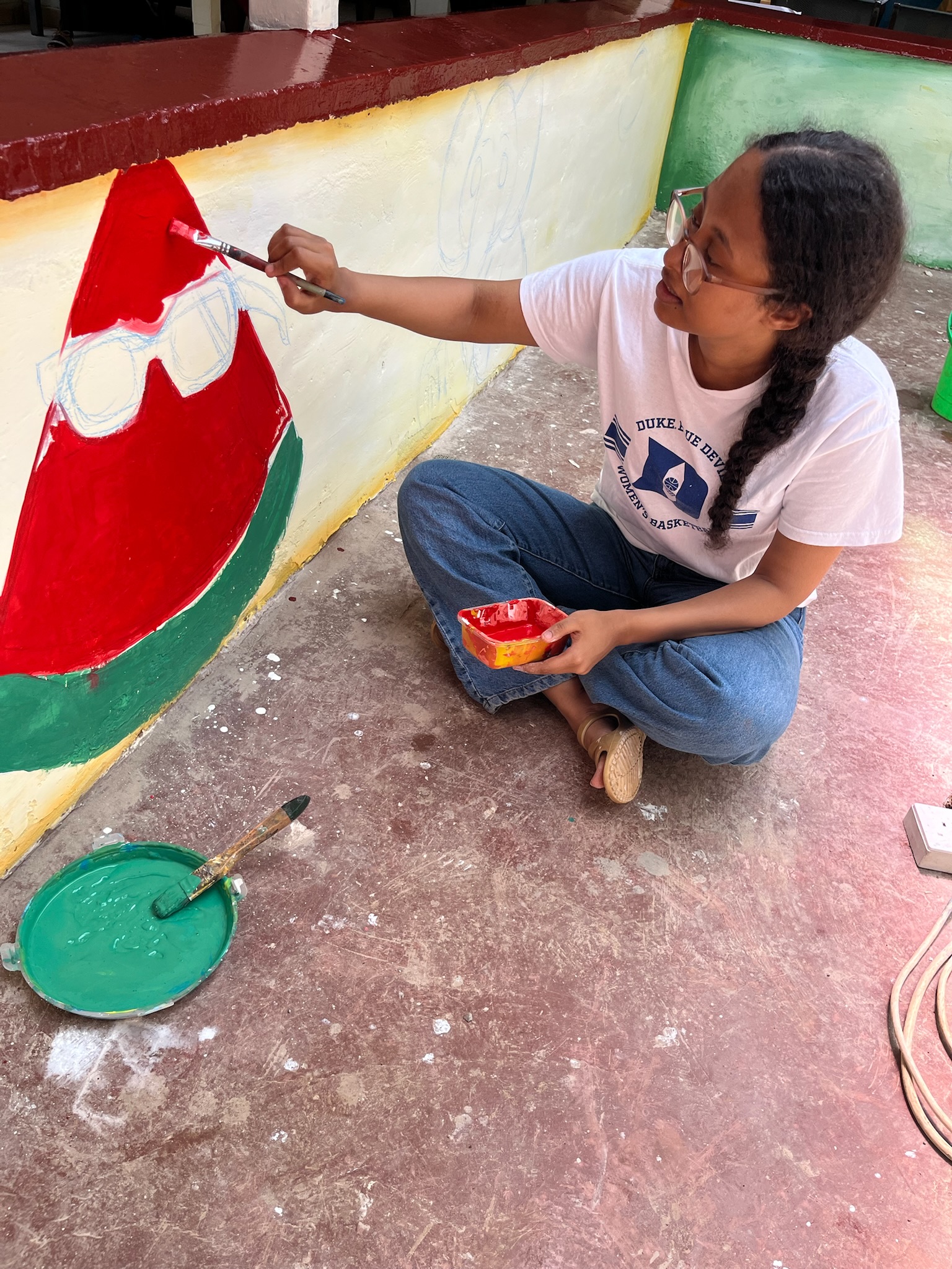 Volunteer painting outdoor murals at Lumumba Hospital